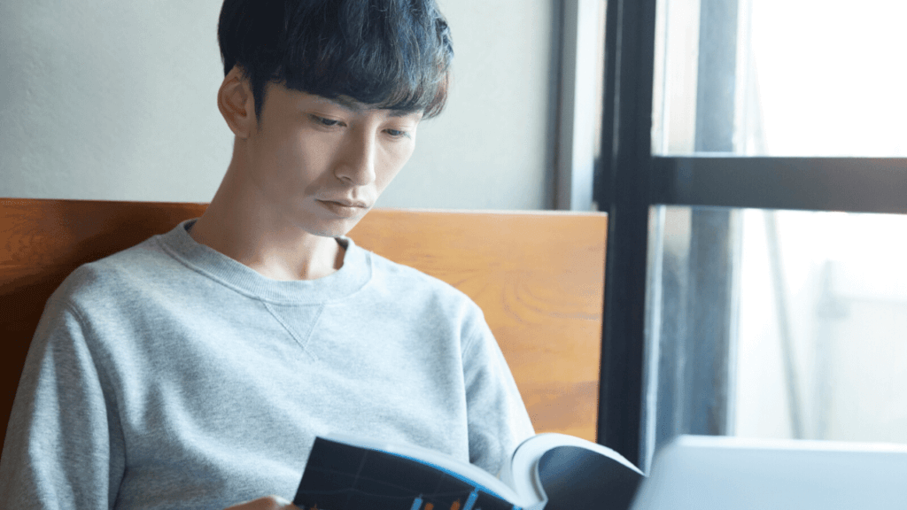 本を読んで仕組債を調べている男性